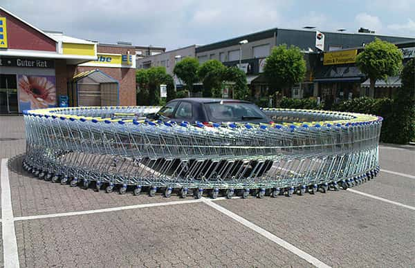 Carrinhos de supermercado foram colocados em volta de um carro estacionado