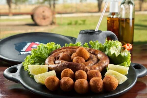 Linguiça de pernil fabricação própria, artesanal um pouco apimentada, servida com bolinho de mandioca. Foto: Embaixada de Minas