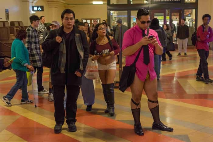 Homem sem calças observa celular durante o evento No Pants Metro Ride, em Los Angeles.
