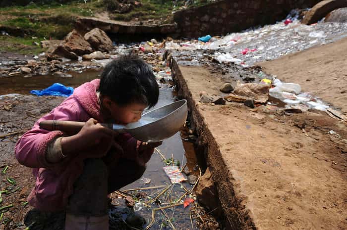 Menino no rio poluído (Foto: Reuters)