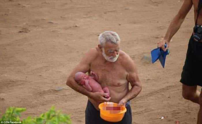 Avô segura o bebê ainda com o cordão umbilical