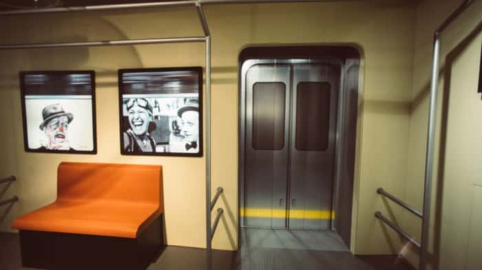 Sala que reproduz vagão de metrô, com fotos de Adoniran nas janelas