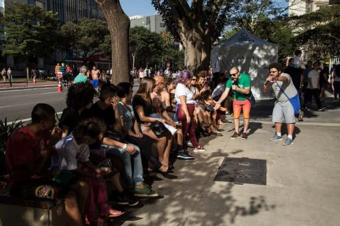 Poetas Ambulantes se apresentam para pessoas sentadas na avenida Paulista