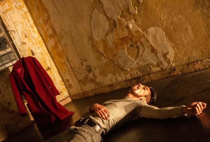 Foto do espetáculo “Sardónico”, em que um dançarino está deitado no chão com uma mão no peito