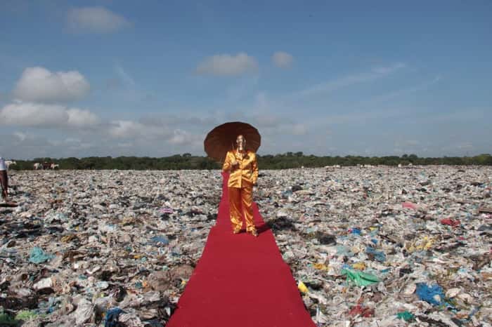 homem com sombrinha em cima de tapete vermelho sobre pilha de lixo
