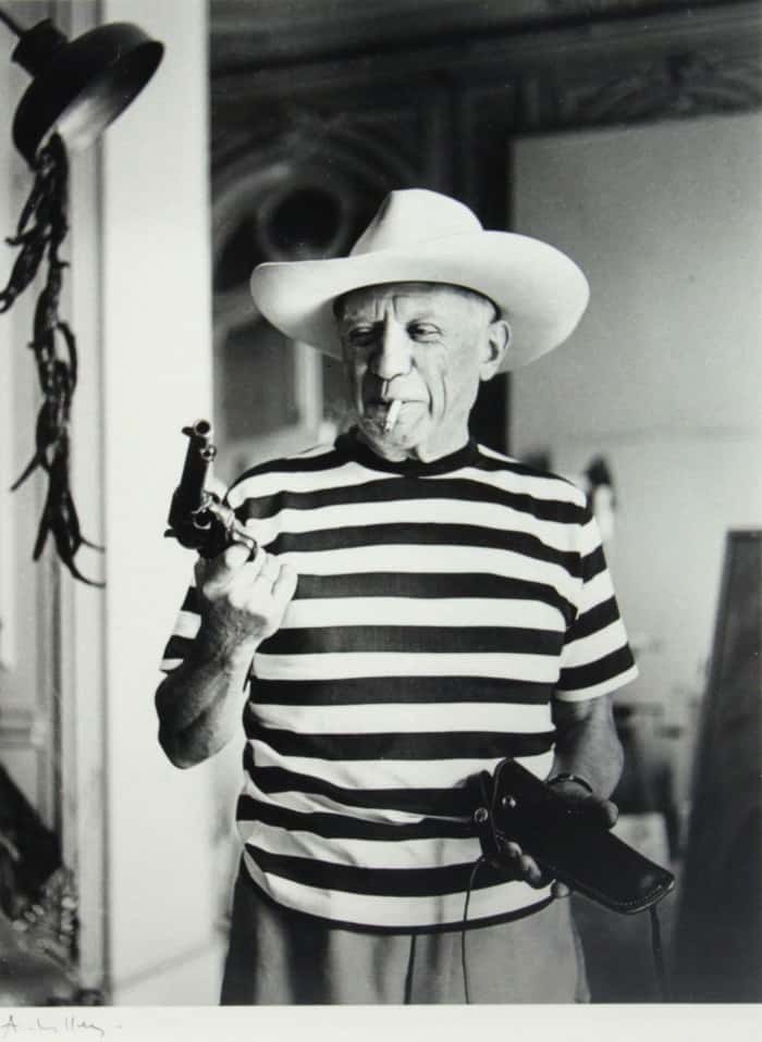 Pablo Picasso de chapéu segurando pistola