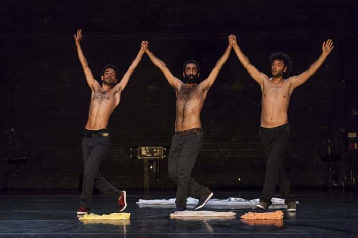 Espetáculo “Displacement”, de Mithkal Alzghair, com três bailarinos em cena de mãos dadas e levantadas para o ar