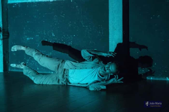 Bailarino deitado no palco com uma luz azul
