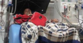 Idoso se protege de goteira com guarda-chuva em hospital