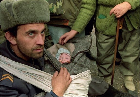 Um soldado bósnio cuida de um bebê que ele salvou durante a evacuação de Gorazde. [1995]