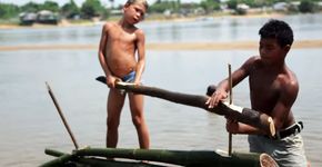 Às margens do rio Xingu, crianças de uma vila de pescadores constroem jangada
