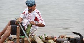 Em jangada, comerciante recolhe lixo de lago em Guarulhos