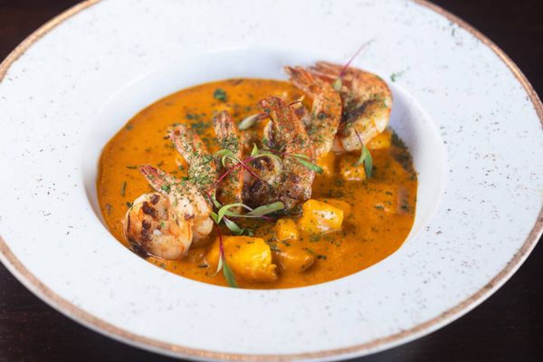 Moqueca de peixe com camarões (R$89), cozida lentamente em caldo de azeite de dendê e leite de coco, acompanhada de arroz branco e farofa com bacon e banana