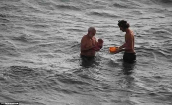 Avô e pai tiram a criança do mar após o parto