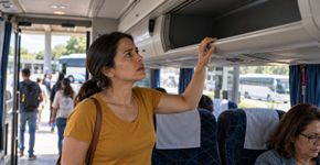 Passageira coloca uma mala pequena no bagageiro do ônibus, desce durante uma parada para comprar água e retorna encontrando outra pessoa sentada no lugar enquanto a bagagem desapareceu