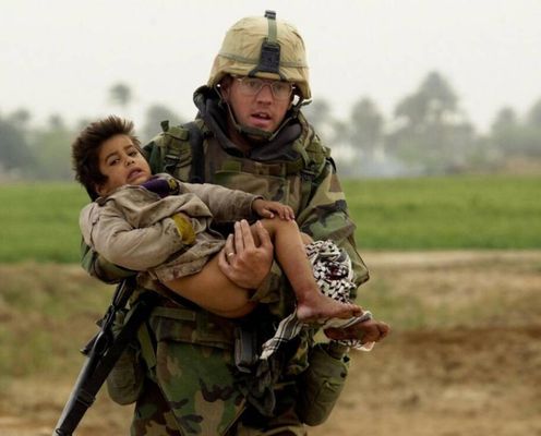 Joseph Dwyer carrega um menino ferido para longe do fogo. [Guerra do Iraque, c. 2003 - 2011]