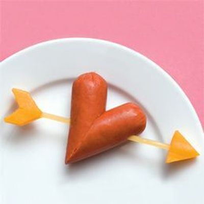 Corte uma salsicha na diagonal. Junte as duas partes e fixe-as com um palito. Nas pontas do palito, queijo cortado em formato de flecha.