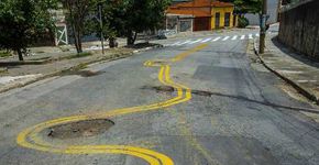 Moradores de rua esburacada pintam ao redor dos buracos em SP