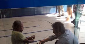 Funcionário de banco se senta no chão para atender cliente