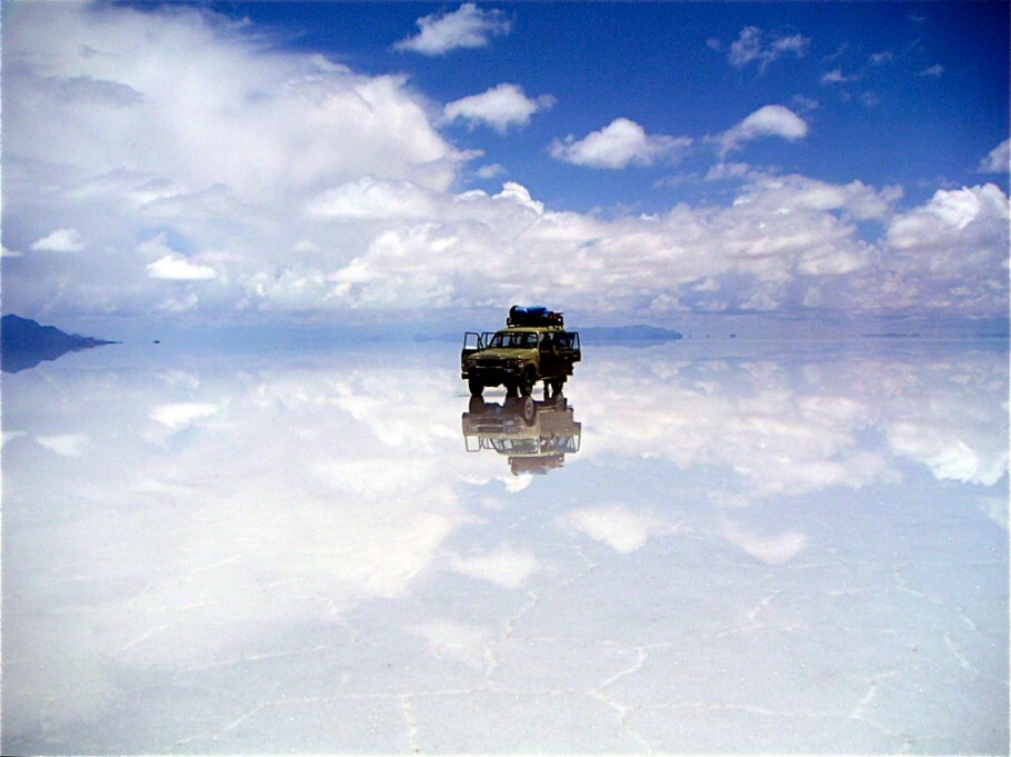 No verão, uma fina capa de água de degelo dos Andes forma um tapete espelhado sob os pés dos visitantes, no Salar do Uyuni