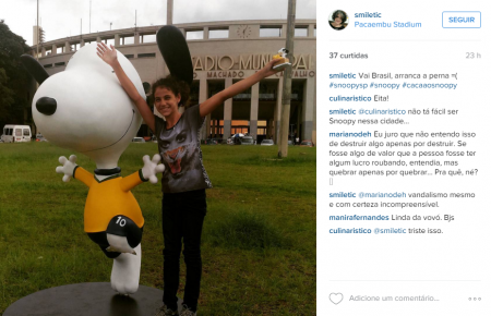 Na foto, uma garota aparece ao lado da estátua do Snoopy localizada no Pacaembu. Como você pode ver, uma perna do cãozinho foi totalmente depredada