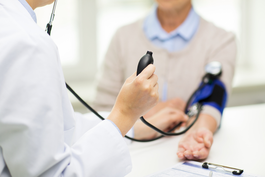 medicine, age, health care and people concept - close up of doctor with tonometer checking senior woman blood pressure level at hospital
