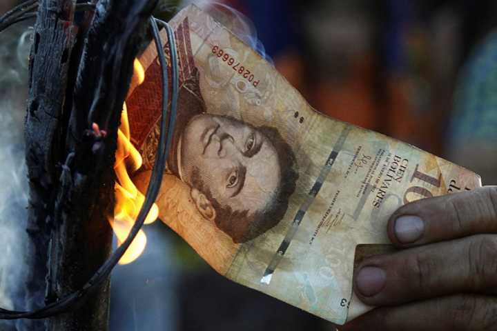 Homem queima nota de 100 bolívares venezuelanos durante protesto em El Pinal (16/12/2016)