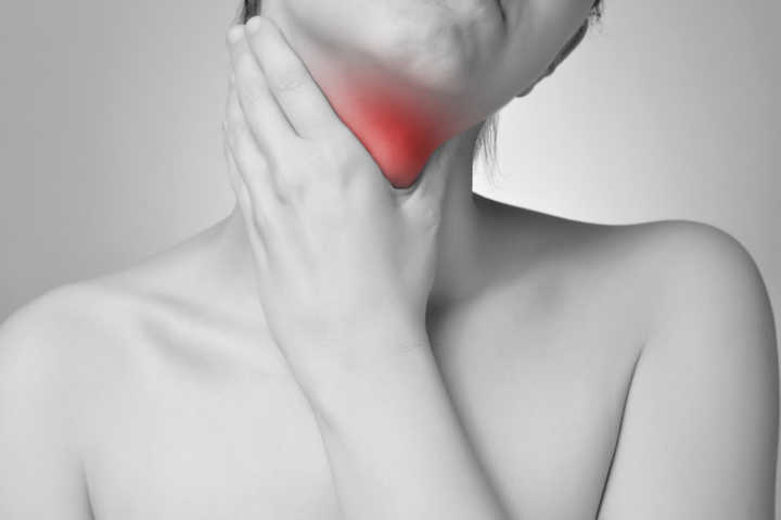 Mulher sente dor de garganta, um dos sintomas da doença