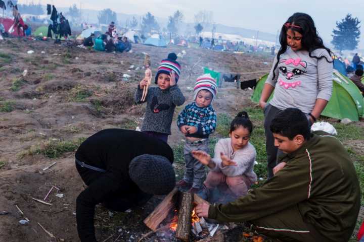 Família tenta se aquecer em campo de refugiados na Grécia