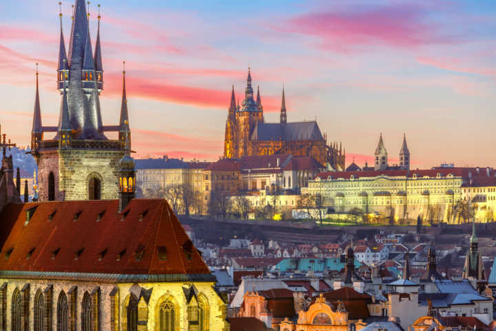 Vista da cidade de Praga com as torres da igreja gótica de Nossa Senhora de Týn em destaque; ao fundo, a Cidade Velha e o castelo de Praga
