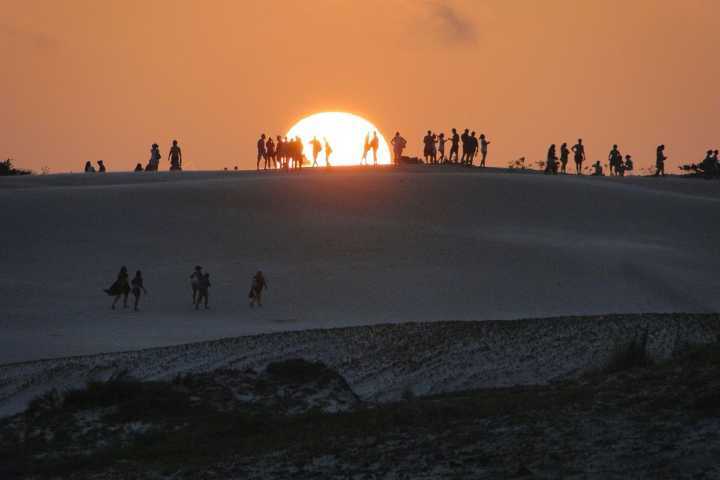 Turistas assistem pôr do sol nas dunas