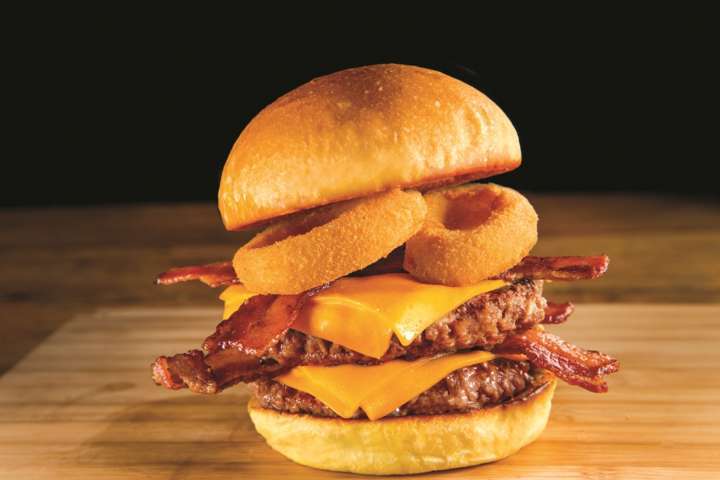 O Smoke House é feito com atias de bacon, onion rings, queijo cheddar e molho smoke house barbecue-ranch