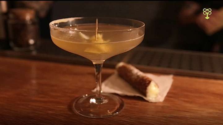 Leave The Gun, Take The Canolli, se inspira na frase do filme O Poderoso Chefão para criar uma releitura do tradicional doce com bourbon, xarope de pão de gengibre, licor 43, limão e açúcar gelado na borda do cop