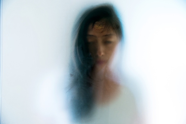 Imagem de uma mulher atrás de um vidro embaçado