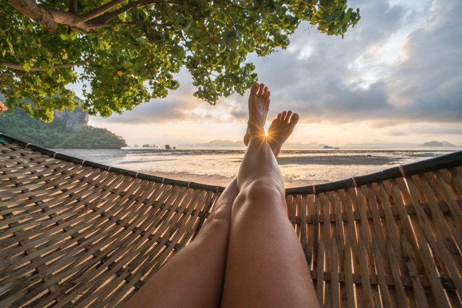 Female’s point of view from hammock on the beach at sunrise, barefoot.