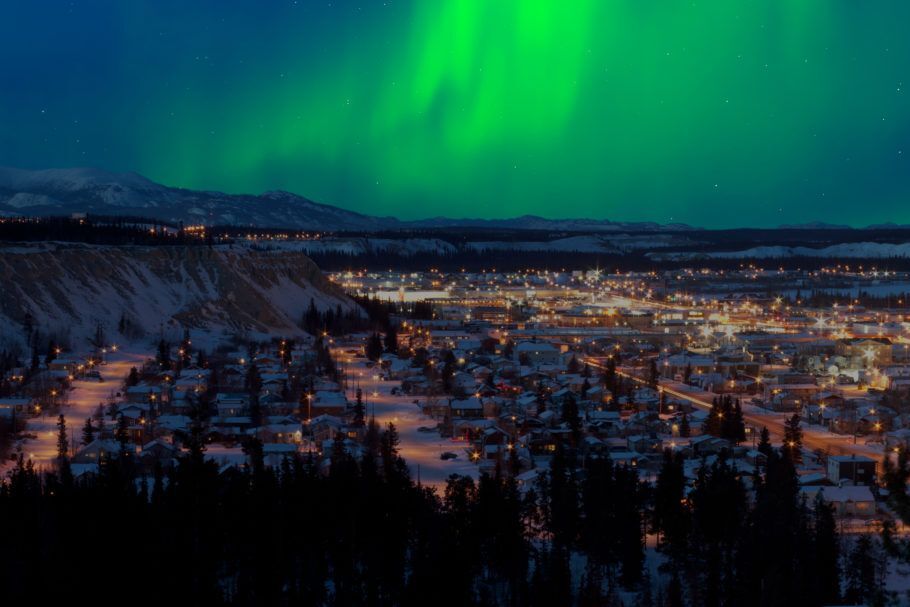 A cidade de Whitehorse, Yukon, no Canadá, com aurora boreal ao fundo