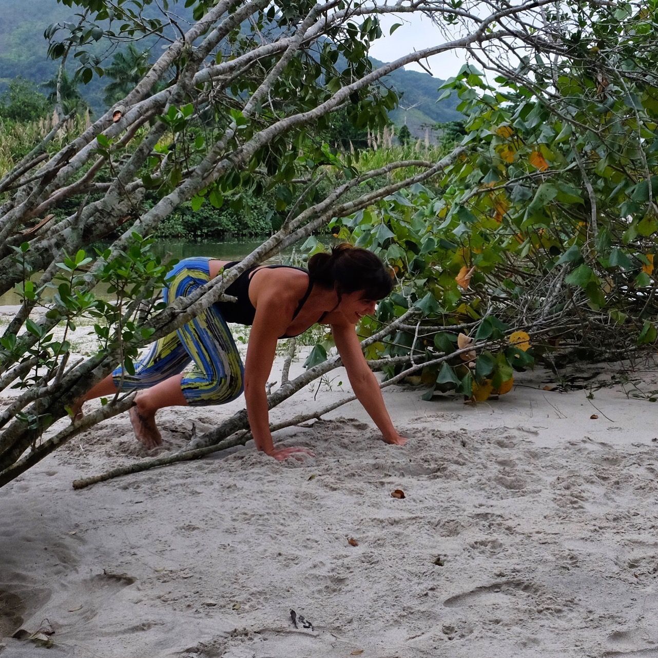 mulher passando sob galhos secos de árvores