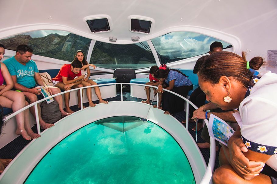 Turistas observam o mar em janela no fundo do barco