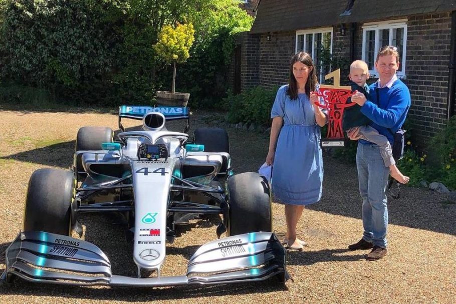 O pequeno Harry Shaw e sua família com o carro de F-1 que ganhou do piloto  Lewis Hamilton