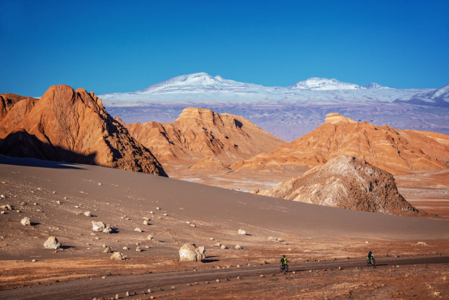 Turistas de bike em uma estrada no Vale da Lua, no deserto de Atacama, com Cordilheira dos Andes ao fundo