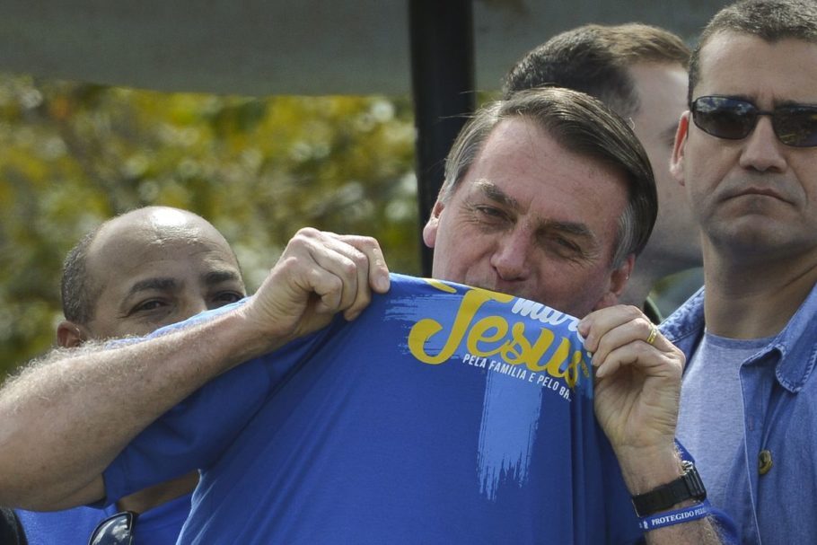 Bolsonaro beijando uma camisa azul escrita Jesus