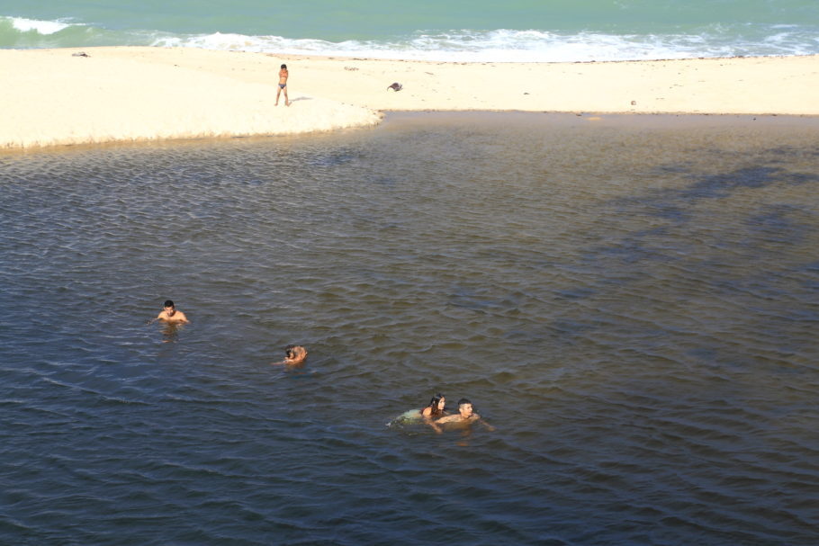Turistas brincam na lagoa de água doce ao lado da praia