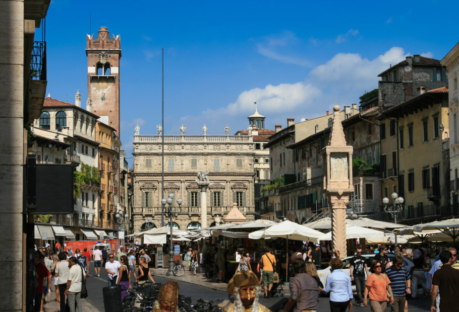 Turistas na Piazza delle Erbe , no centro de Verona, na Itália, com o Palazzo Maffei ao fundo