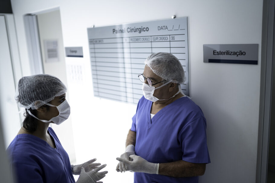 médicos com máscaras e luvas no corredor de hospital