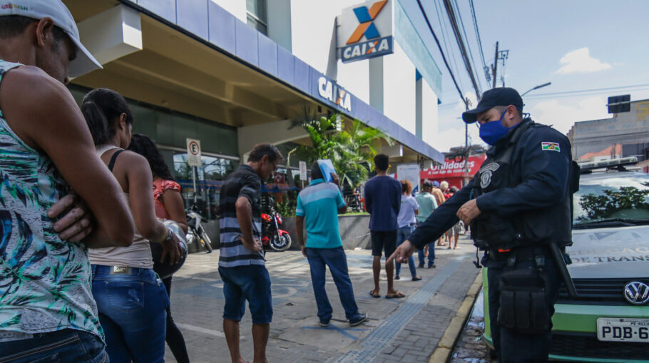 Guarda municipal da cidade de Caruaru (PE) orienta pessoas a manterem distância enquanto aguardam atendimento da Caixa