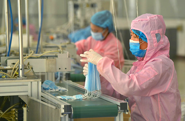 Os funcionários na linha de produção de máscaras de empresa na China