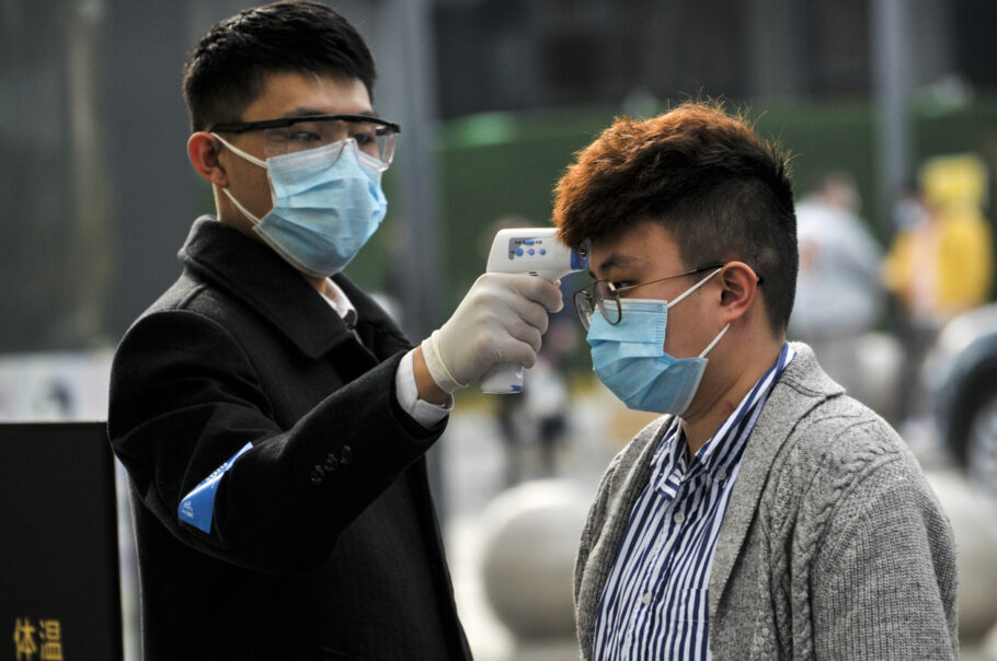 Segurança mede temperatura em entrada de shopping de Wuhan, cidade onde começou a pandemia de coronavírus
