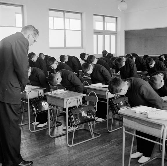 Meninos de uma escola católica no Japão curvam-se ao seu professor em sinal de respeito nesta imagem de 1956