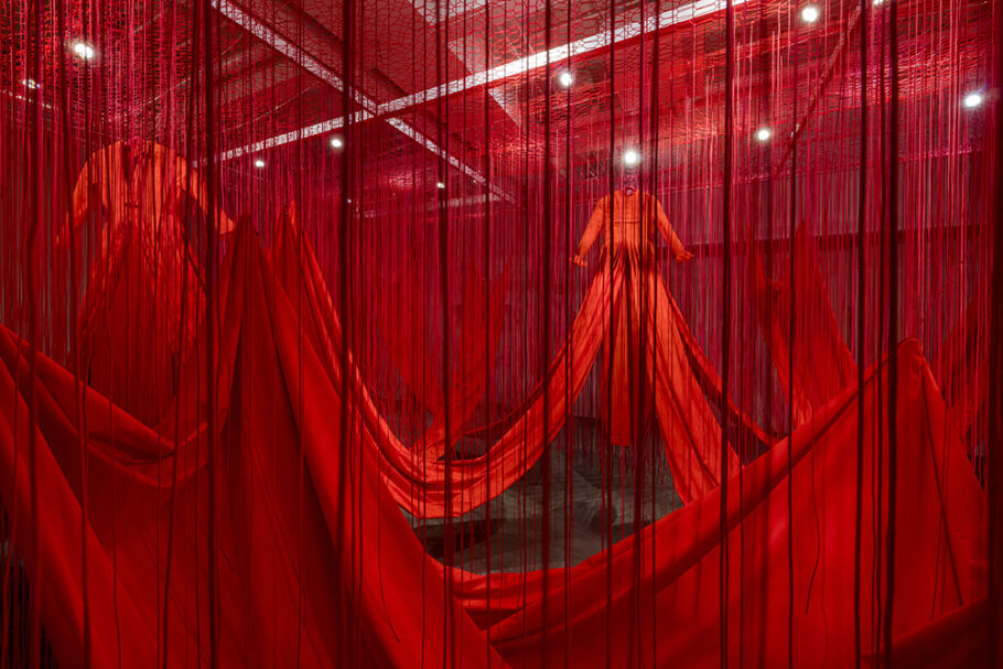 Em “Linha Interna” (2019), três grandes vestidos vermelhos e cerca de 10 mil fios pendurados verticalmente totalizam mais de 34 quilômetros de material!