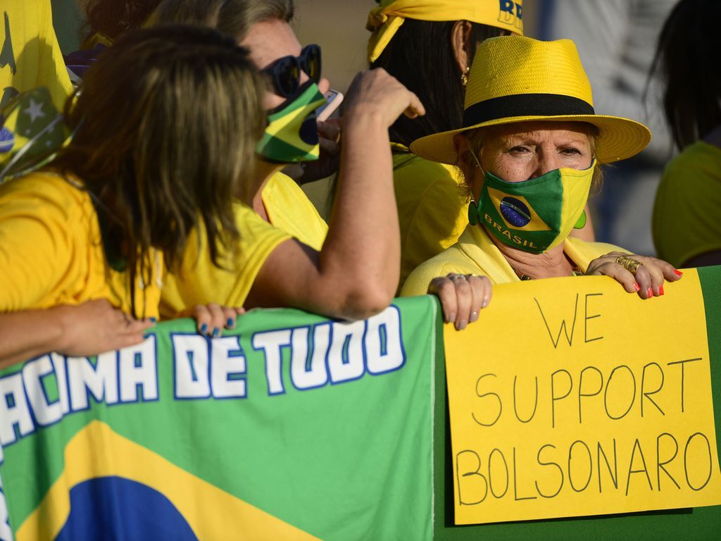 Mulher levanta cartaz “We support Bolsonaro” (nós apoiamos Bolsonaro) nas manifestações
